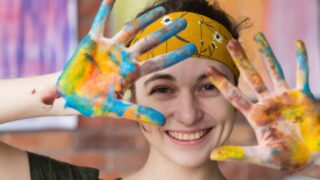 girl holding up painted hands while showcasing Creative-Therapy-Games-and-Activities-For-Teens
