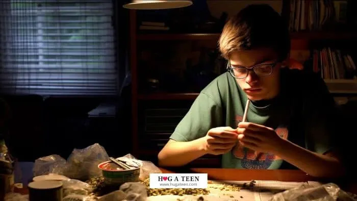 A teen sitting alone in a room rolling a marijuana cigarette