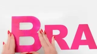 Hands holding up pink letters that spell BRA - Teen Sports Bra Guide